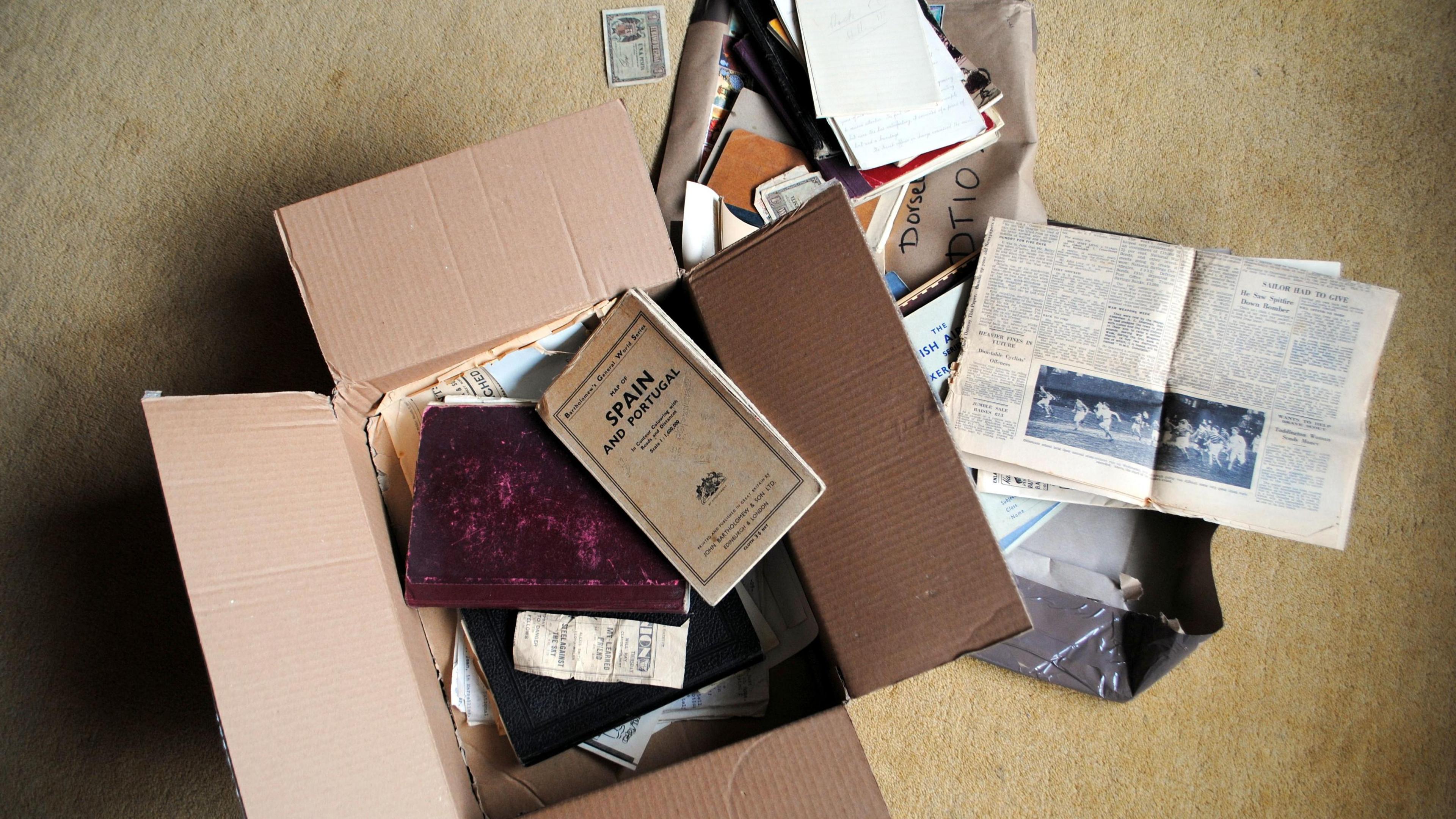 A cardboard box full of note pads and newspaper clippings