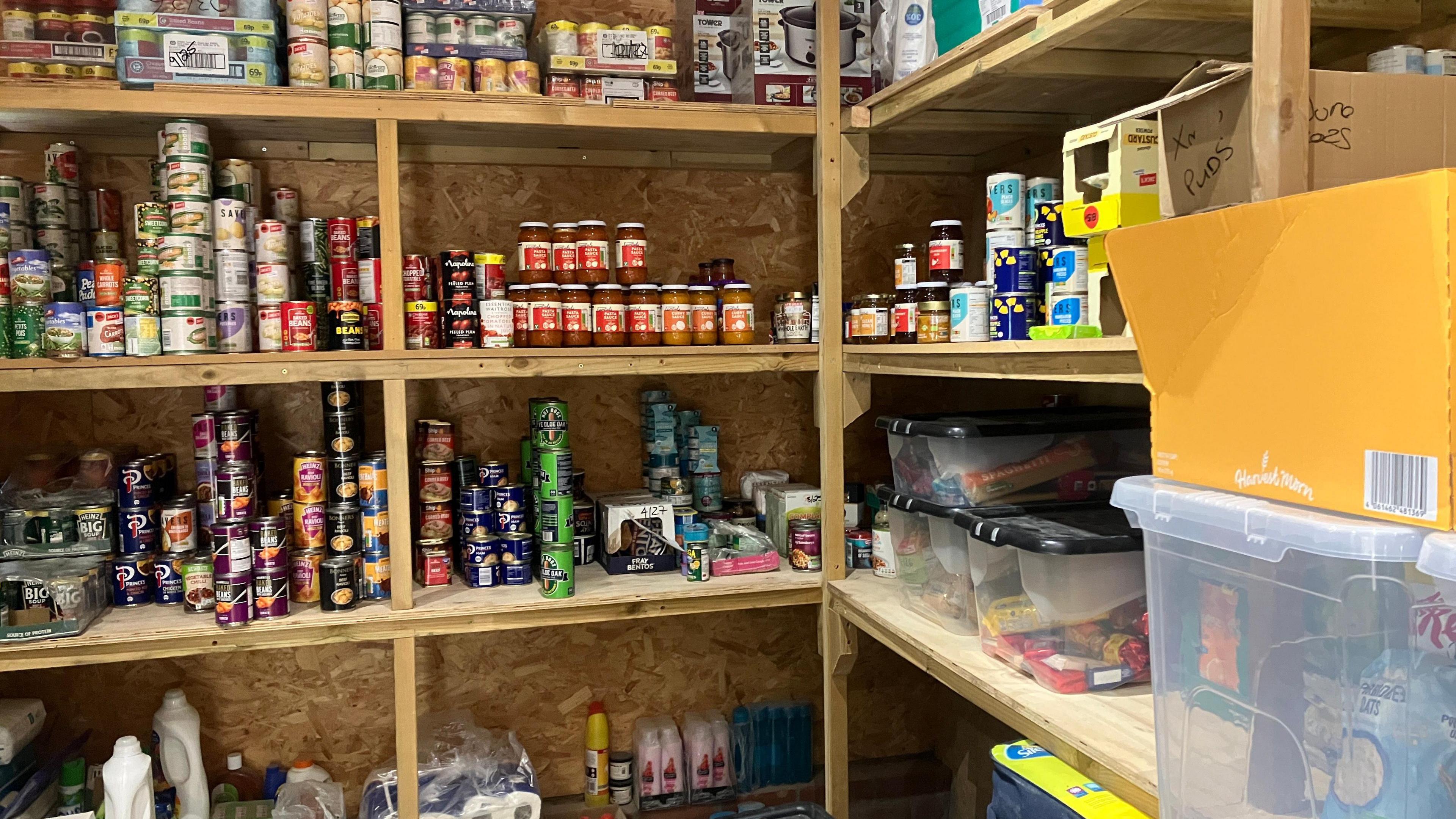 Shelves in the foodbank with tins and jars stacked up on them.