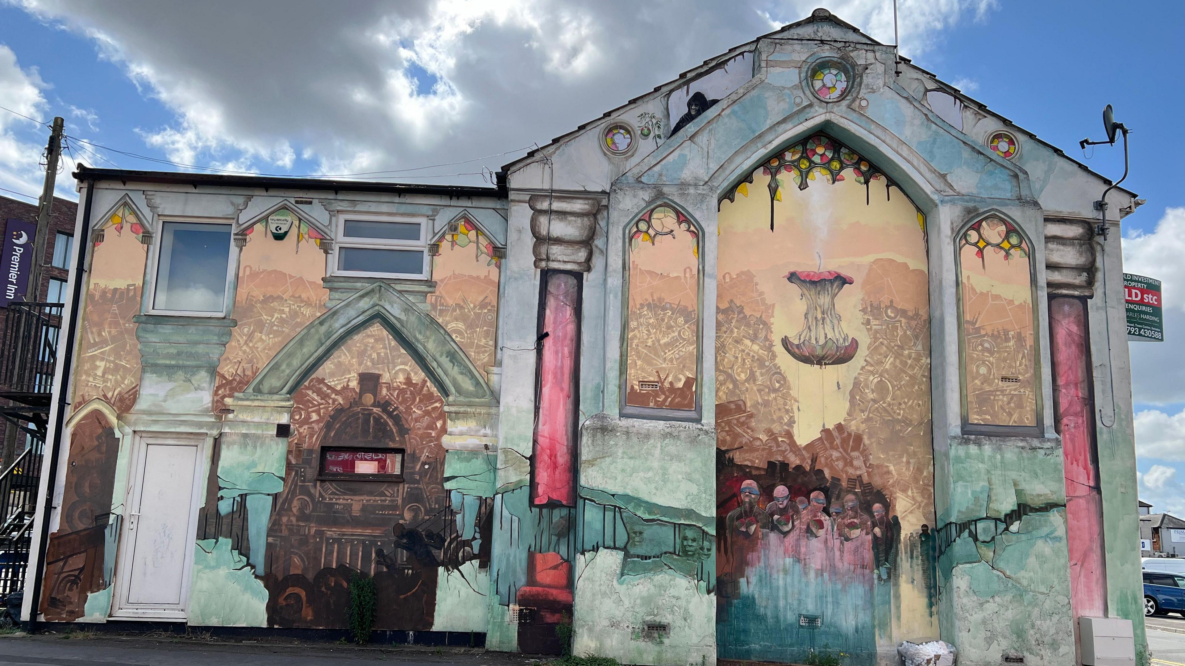 Mural on the side of a house, which is meant to look like the view through a church, with a giant floating apple core at its centre.