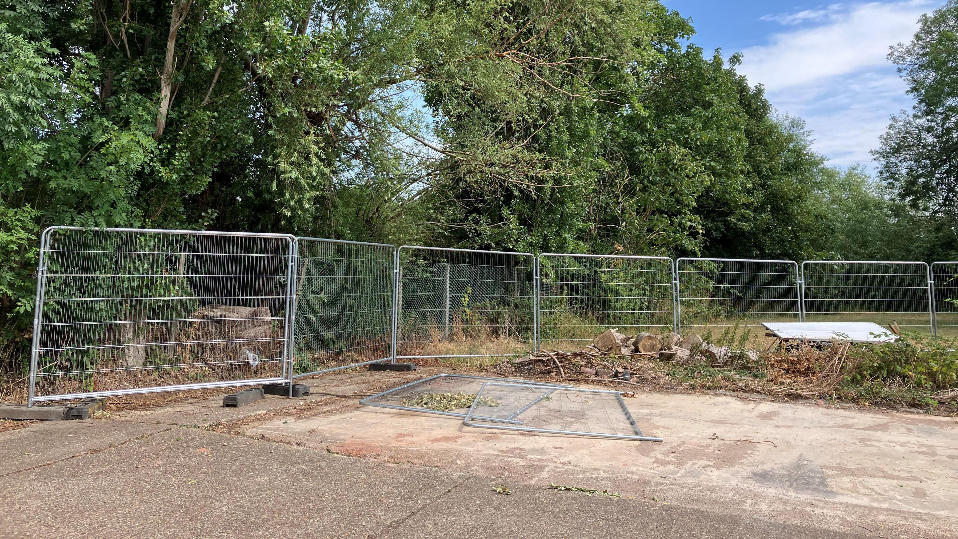 A concrete space with temporary metal wire fencing round the edge.