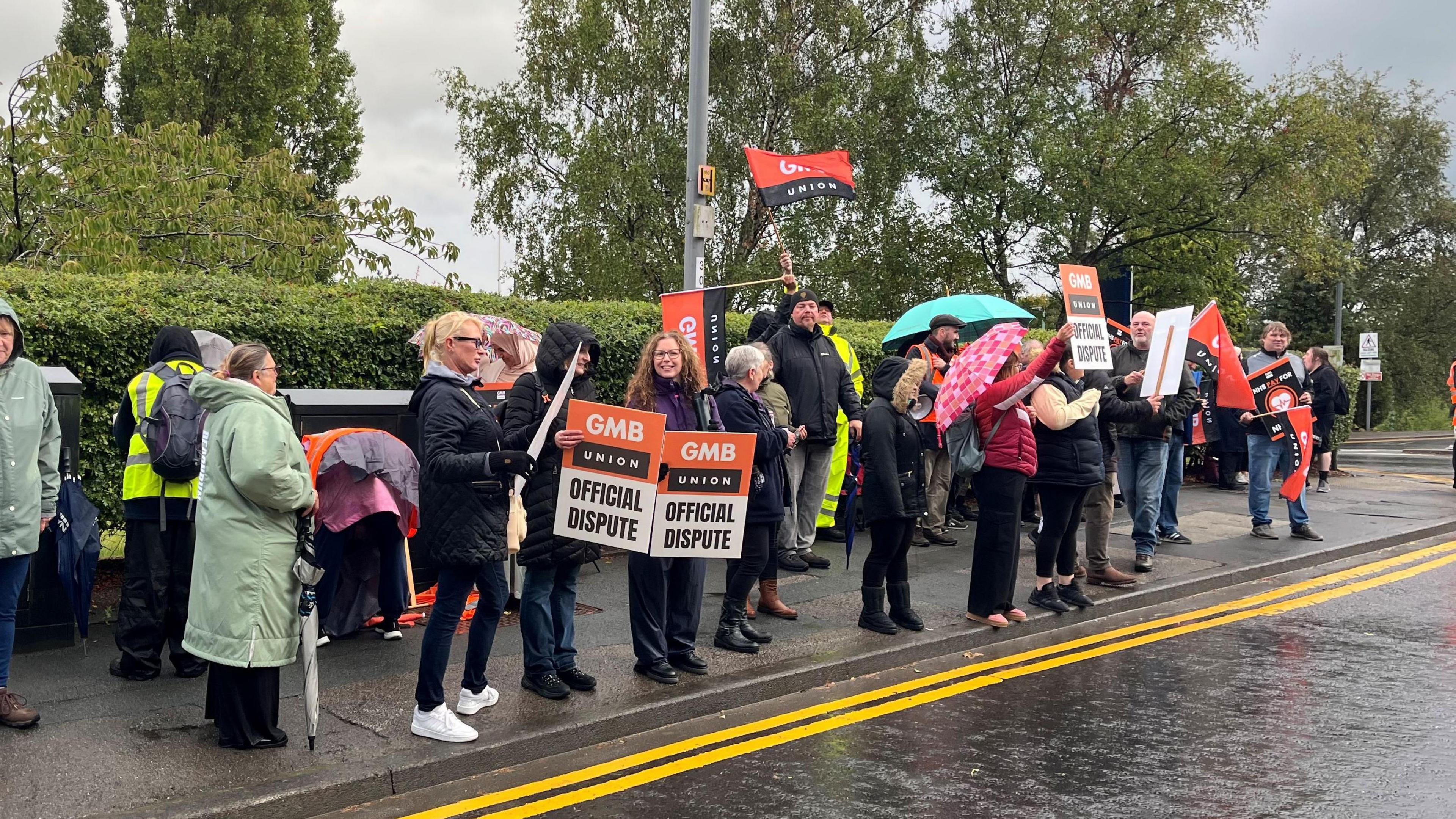 A picket line, with striking workers holding posters saying "GMB union official dispute".