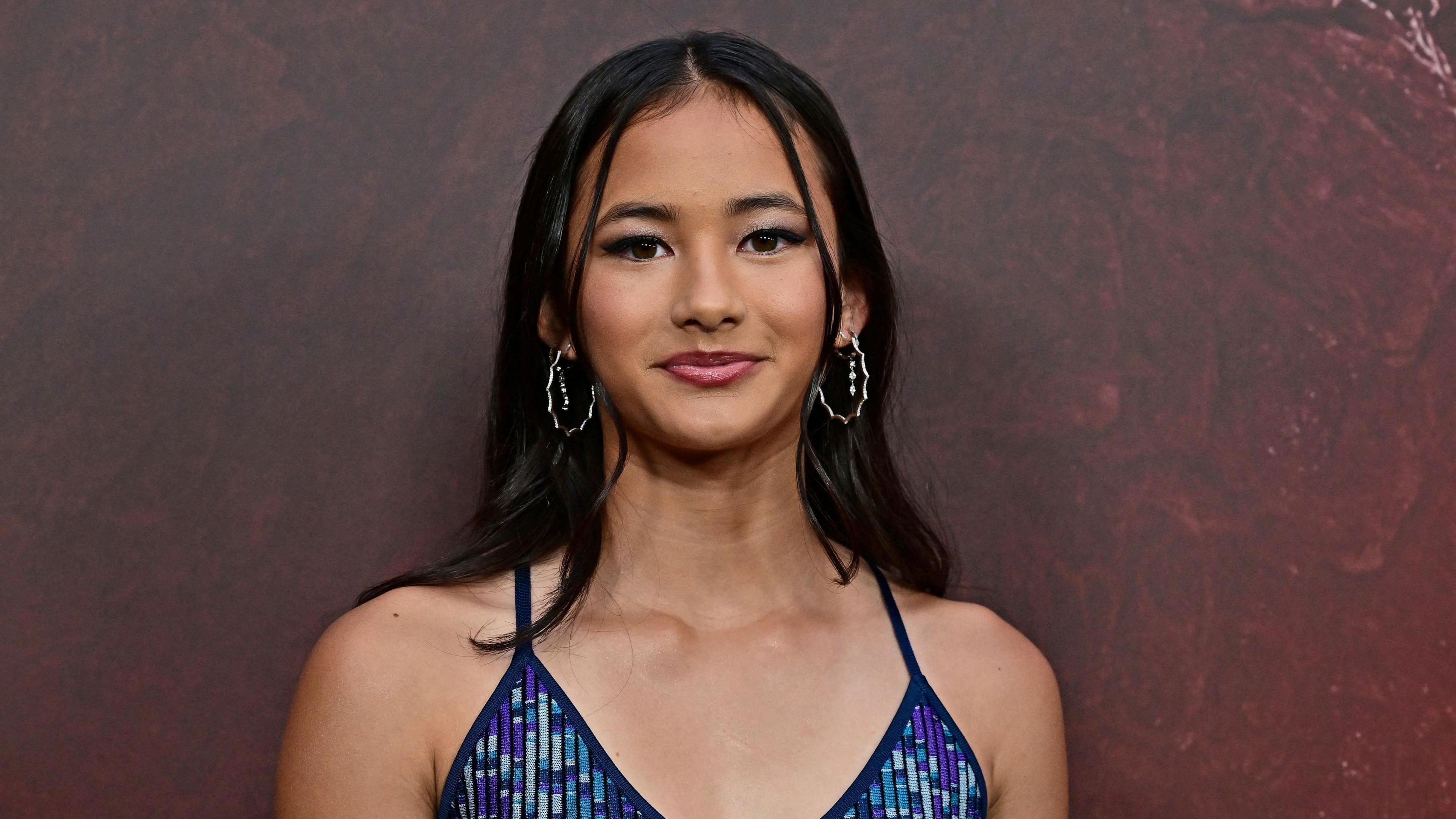 Kaylee Hottle wears a blue and purple sparkly dress and silve hoop earrings.