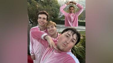 The members of Boy Throb are posing for a selfie photo. They are all dressed in a pink velour tracksuit with white detailing.  Darshan is photoshopped in to the top of the photo and he is holding his hands in a heart. 