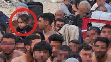 A zoomed-in image shows a group of Gazan men, in Israeli detention and sitting outdoors against the backdrop of a destroyed building. A little girl is there, circled in red by the 91ȱ in this image, for clarity.