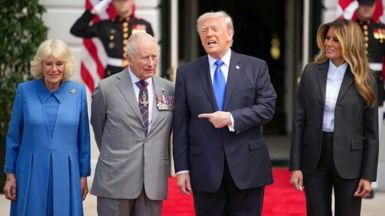 Queen Camilla, King Charles III, President Donald Trump and First Lady Melania Trump stand on a red carpet outside the South Portico of the White House with soldiers and US flags behind.