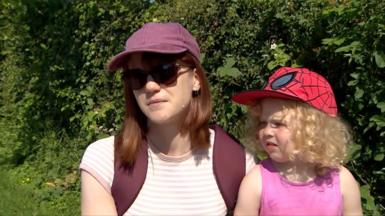A woman and her daughter are interviewed while sitting next to a hedge.