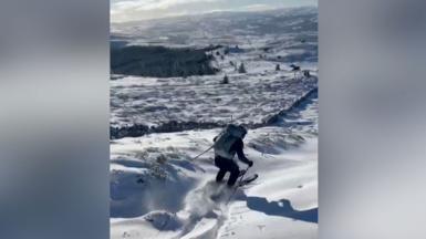 A man travels down a snow-covered mountain on skis.