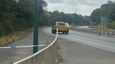 The closed section of the A66. A police car is parked on the silent, empty, dual-carriageway.