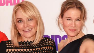 Helen Fielding (L) and Renee Zellweger attend the world premiere of Bridget Jones's Baby at Odeon Leicester Square in London in 2016. They both have blonde hair and are wearing black dresses. Both are smiling and looking at the camera.