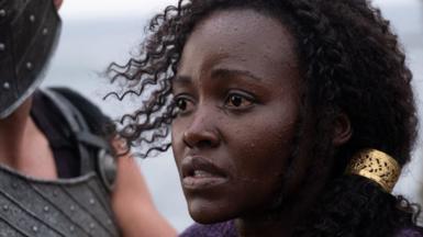 Lupita Nyong'o looks to the left of frame in a concerned manner, in a close head and shoulders shot as she stars as Helen of Troy in Christopher Nolan's The Odyssey.