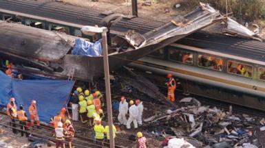 Image shows the destruction caused by the crash with emergency rail workersin hard hats and high vis on the track