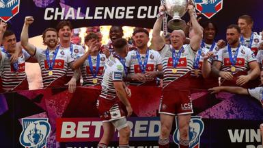 Wigan Warriors players lift the Challenge Cup trophy