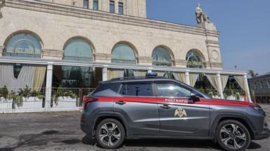 A grey car law enforcement car is parked outside a building in Moscow