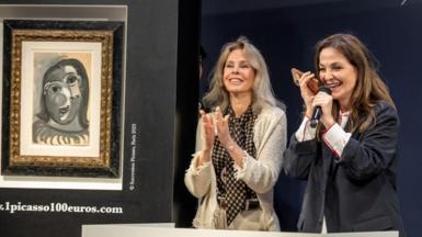 Two auctioneers stand next to a Picasso painting