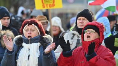 Two women take part in a demonstration against plans to open a battery factory in Debrecen
