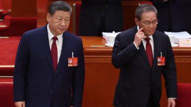 China's President Xi Jinping standing next to Premier Li Qiang as they take their seats at the opening session of the National People's Congress (NPC) at the Great Hall of the People in Beijing on 5 March
