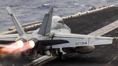 A jet fighter jet takes off from the flight deck of a US aircraft carrier