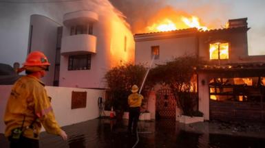 Firefighters try to put out a blaze burning a house in Los Angeles