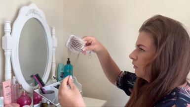 A woman pulling hair out of a hair brush