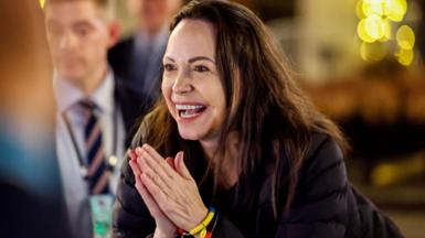Machado smiles as she looks at a supporter and holds her hands together in a prayer motion