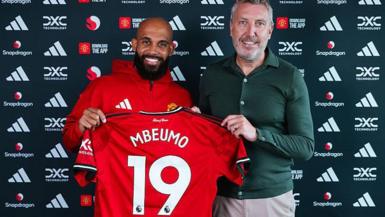 Bryan Mbeumo holding up a Manchester United shirt next to director of football Jason Wilcox.