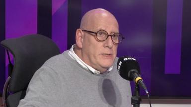 Bald headed man with glasses in a BBC radio studio. 