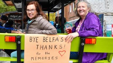 Passengers of the cruise ship smiling on a beer bike in Belfast with a sign that says 'Bye Belfast, thanks for the memories'