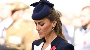 The Princess of Wales bowing her head. She is wearing a navy jacket with a poppy pinned to the lapel