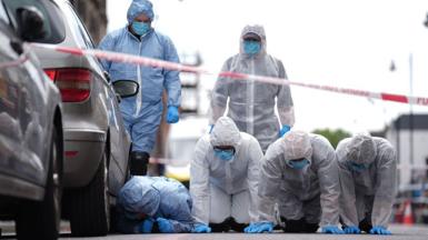 Forensic police officers survey the scene in Hackney on Thursday