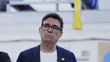 Headshot of Burnham who looks up and to the right. He has a serious expression. The background is blurry.