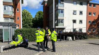 Police officers in hi vis yellow jackets with brown buildings behind them