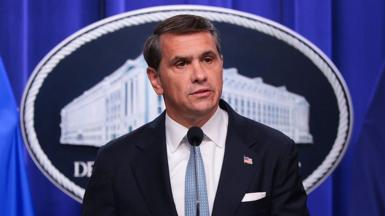 Todd Blanche, wearing a suit and light blue tie, speaks during a news conference at the Robert F. Kennedy Department of Justice building.