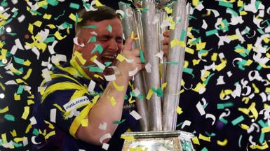 Luke Littler celebrates winning the 2026 PDC World Championship as tickertape falls