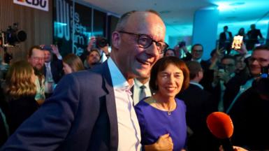 Friedrich Merz and his wife Charlotte talk to journalists