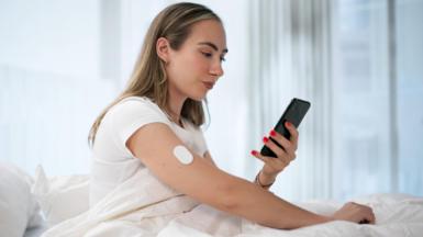 A woman checks her blood glucose reading using her mobile phone app