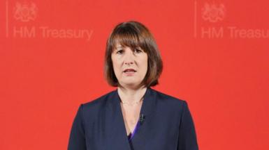 Rachel Reeves looking slightly apprehensive against a red "HM Treasury" background