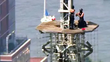 A man and a woman are seen during a proposal on top of the top of the Empire State Building.