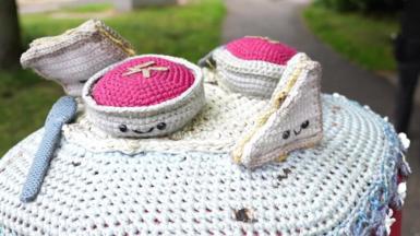 A knitted tea set complete with a spoon and sandwich on top of a letter box