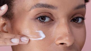 Woman applying cream to her face