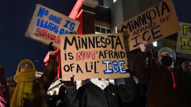 Protesters hold signs that reads "Minnesota is not afraid of a lil' ICE".