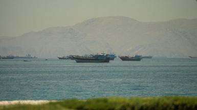 Boats in the Strait of Hormuz, seen from Oman, with mountains behind