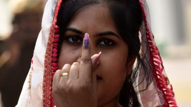 A woman shows her ink-marked finger after casting her vote