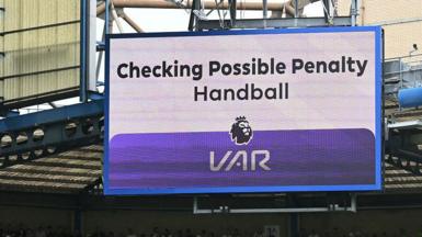 A big screen display a VAR check for a possible penalty during a Premier League match
