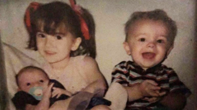 A young girl and boy, Meaghann and William Murphy when they were children, smiling at the camera. Meaghann is holding baby Rebekah Simpson. 