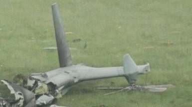 The tail of a grey military helicopter which has crashed in a field in Devon. Wreckage can be seen across parts of the grass.