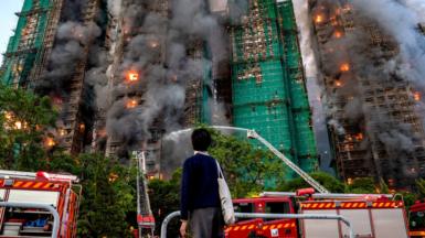 A student watches as smoke and flames rise as a major fire engulfs several residential buildings at Wang Fuk Court
Single use only on this story, can be syndicated