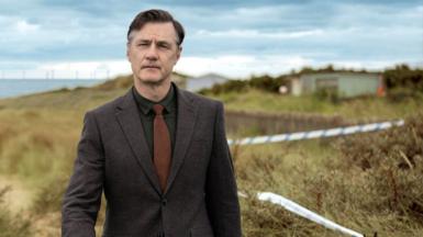 David Morrissey wearing suit walks across field in scene from BBC drama Sherwood