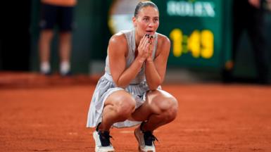 Marta Kostyuk crouches down with her hands on her face after completing victory over Elina Svitolina