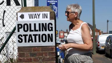 A woman wearing a white vest top enters a polling station in Clacton-on-Sea.