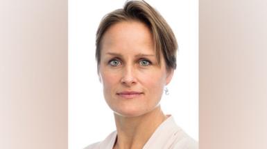 Portrait of new MI6 chief portrait of Blaise Metreweli. She has short, dark, asymmetric hair and blue eyes. She has a subtle smile as she looks directly at the camera, against a white background.